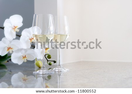 white wine in glasses on countertop - orchids in background - room for copy