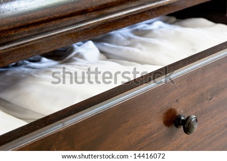 open wooden dresser drawer with white clothes