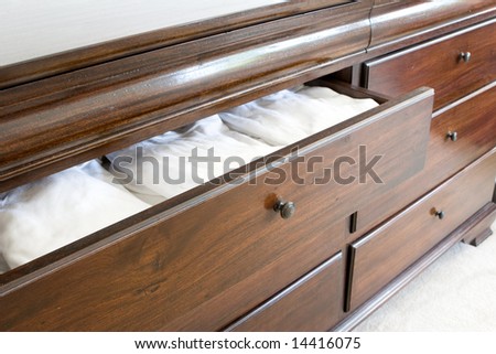 open wooden dresser drawer with white clothing