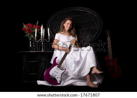 woman in bridal dress sitting on chair with guitars, roses, candles, & wine - black background