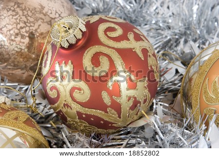 red and gold christmas ornament on bed of tinsel