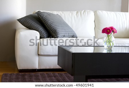 modern white living room with vase of pink daisies