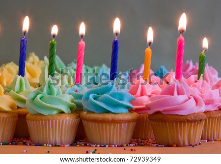rainbow cupcakes with lit birthday candles