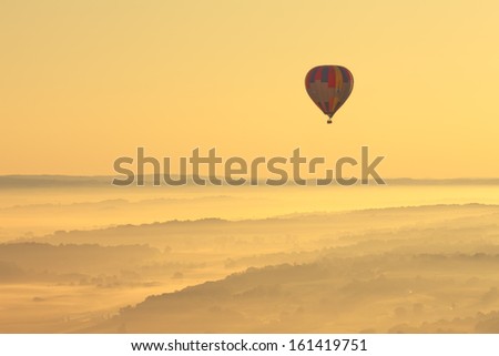 Beautiful aerial view of the Amish landscape and a hot air balloon in Pennsylvania with a gorgeous misty morning yellow sunrise