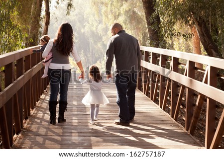 Happy Family Walking Away Towards A Forest On An Old Wooden Bridge - Mother, Father, Two Daughters