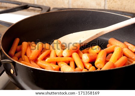 Sauteing of orange baby carrots in olive oil