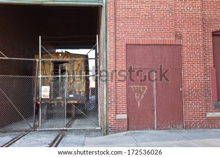 Abandoned WWII factory with train tracks and old train behind chain link fence located in Martinsburg, WV