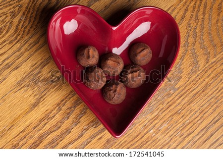 Top view of a heart shaped bowl filled with dusted chocolate truffles