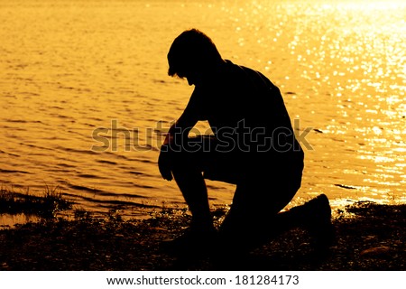 Silhouette of teenage boy kneeling down