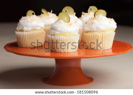 Retro vintage orange platter with Coconut Key Lime Cupcakes - Coconut cake with a key lime filling topped with a light 7 minute frosting, toasted coconut, and a slice of candied key lime