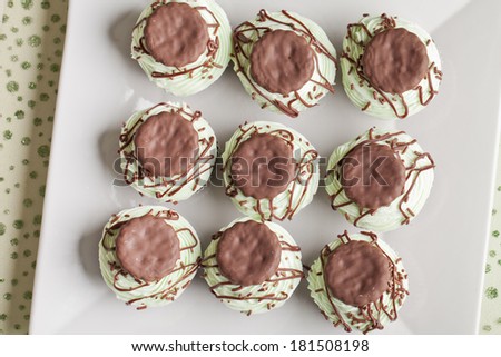 Top view of Irish Mint Cupcakes - Chocolate cake with thin chocolate mint cookie pieces filled with mint topped with green mint buttercream frosting, a dark chocolate drizzle, and mint cookies