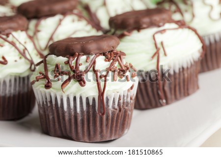 Irish Mint Chocolate Cupcakes - Chocolate cake with chocolate mint cookie pieces filled with mint topped with a green mint buttercream frosting, drizzled with dark chocolate, and a cookie thin cookie