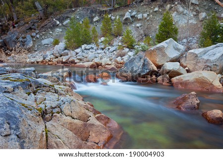 Beautiful serene soft flowing water set against red and granite rocks with green moss growing on them