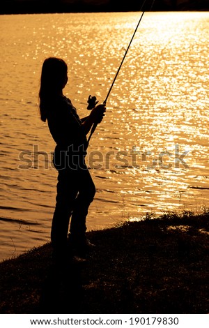 Silhouette of a teenage girl fishing at sunset