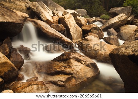 Soft water cascading down golden brown rocks along the Merced River
