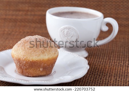 Cup of dark hot chocolate with a white muffin dipped in butter and rolled in cinnamon sugar