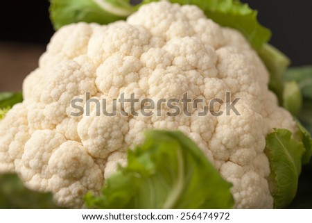 Macro shot of freshly harvested head of organic cauliflower with vibrant green leaves