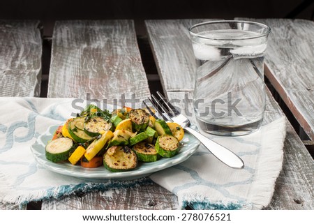 Vegan meal of a plate of freshly sauteed summer vegetables on an old barn wood table