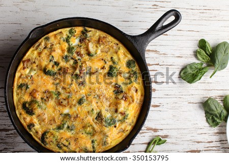 Baked egg frittata with spinach, cheese, broccoli, red potatoes, bacon, milk, and spinach top view