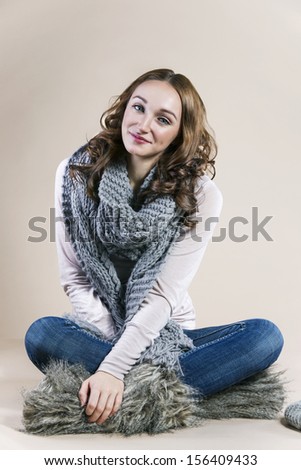 Girl siting on the floor, she is dressed in sweater, scarf and fur boots, work in studio