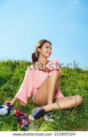 Beautiful young girl sitting on the green grass with roller, work in outdoor
