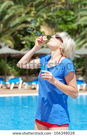 young girl makes soap bubbles by the pool