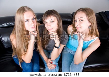 three beautiful attractive girls sitting on the couch and gossip, three friends discuss the article in the magazine, the three friends on the couch talking, laughing girl