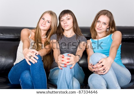 three beautiful attractive girls sitting on the couch and gossip, three friends discuss the article in the magazine, the three friends on the couch talking, laughing girl