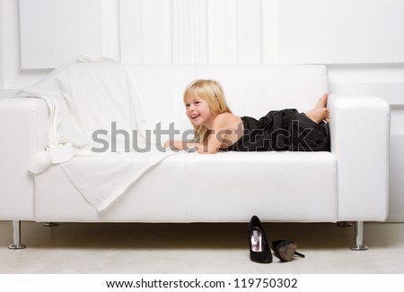 3 years old girl lying on a white sofa in my mother\'s dress, standing next high heels
