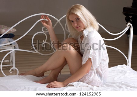 Blonde girl in the bed next to wrought headrest