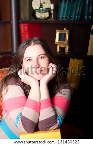 Fat girl in a striped sweater against a bookcase