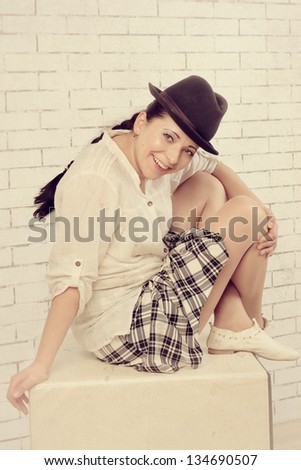 Woman sitting in a skirt, shirt and hat, vintage treatment