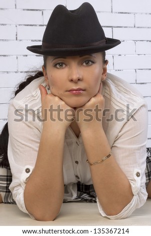 Large portrait of 30 year old woman in a hat, leaning on the face with his fists