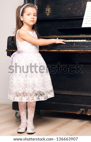 little girl in a beautiful dress near the piano