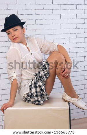 Woman sitting in a skirt, shirt and hat