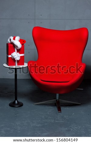 Red empty chair and a table with Christmas present