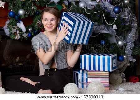 Christmas Gift.Happy Surprised Woman with Gift box at home. Christmas Tree