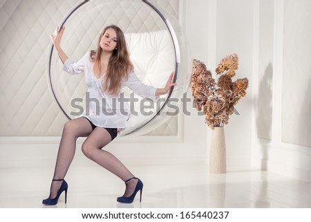 Girl in white tunic sitting in a chair suspended round