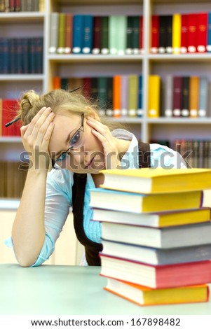 Portrait of clever student with open book reading it in library