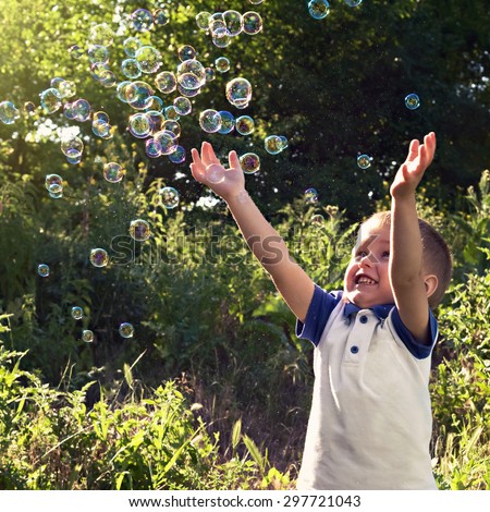 Boy playing catch soap bubbles outdoors