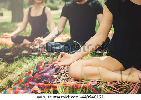 Young yoga practitioners in group doing yoga on nature.