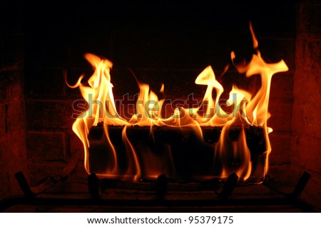 Burning fire log lighting the fireplace and heating a house
