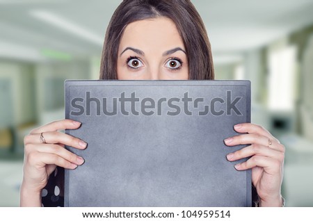 a scared young woman standing behind a folder in her office