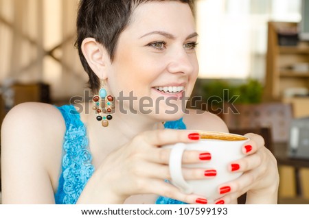 A close up shot of a woman looking forward, as she holds a mug u