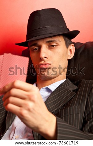 Man with hat playing underground poker on rad background