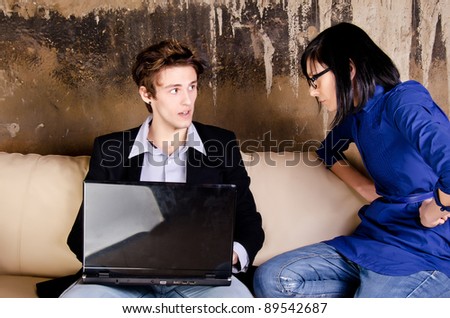 Serious man working on her laptop while her girlfriend is worry