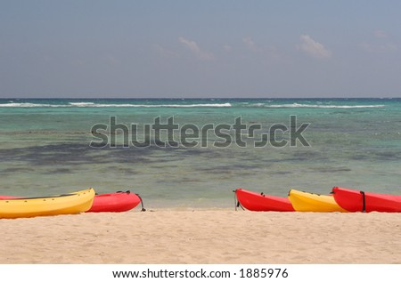 Beach scene with red and yellow kayaks lined up near the water.