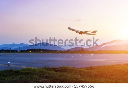 passenger plane fly up over take-off runway from airport at sunset