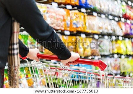 Lady pushing a shopping cart in the supermarket.