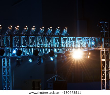 Studio lighting equipment high above an outdoor theatrical performance.